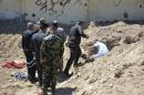 Iraqi security forces including a forensics team work at the site of a mass grave, one of two discovered containing the bodies of dozens of men, women and children killed by Islamic State group militants, in the stadium area in Ramadi, 115 kilometers (70 miles) west of Baghdad, Iraq, Tuesday, April 19, 2016. (AP Photo)