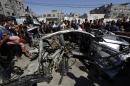 Palestinians gather around a car that was targeted by an Israeli air strike in Gaza City on June 27, 2014