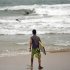 A surfer walks into the ocean as tropical storm Irene approaches to the island in Luquillo, Puerto Rico, Sunday, Aug. 21, 2011. The storm, packing winds of about 50 mph (85 kph) and tracking westward at 20 mph (32 kph), was expected to strengthen and pass near the U.S. island of Puerto Rico later Sunday or early Monday. (AP Photo/Ricardo Arduengo)