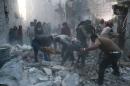 Syrian Civil Defence workers and pedestrians clear debris after an alleged air strike by Syrian government forces in the Bab al-Nairab neighboured of the northern Syrian city of Aleppo on November 12, 2014