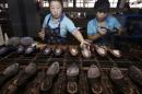Employees apply glue on the bottom part of shoes along a production line at a shoe factory in Wenzhou