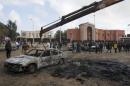 The burnt-out remains of a car is removed from a road at the site of a bomb blast in Shahat
