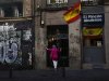 A woman stands next to Spanish flags as she waits to enter a building in central Madrid