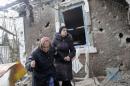 People walk outside a house, which according to locals was recently damaged by shelling, in Donetsk