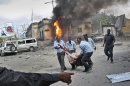 Somali security force members carry away a wounded civilian following a suicide car bomb blast in the capital Mogadishu, Somalia Sunday, May 5, 2013. A Somali police official at the scene said four civilians and a soldier were killed after the suicide bomber attempted to ram a car laden with explosives into a military convoy. (AP Photo/Farah Abdi Warsameh)