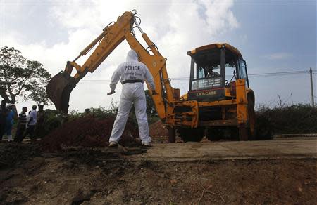 A police officer watches as an excavator digs up skeletons at a construction site in the former war zone in Mannar