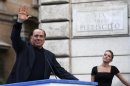 Former Italian Prime Minister Silvio Berlusconi waves to supporters as his girlfriend Francesca Pascale looks on during a rally to protest his tax fraud conviction, outside his palace in central Rome