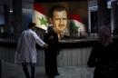 People walk through the Damascus General Hospital past a portrait of the President Bashar Assad in Damascus, Syria, Sunday, May 4, 2014. An official with Syria's Supreme constitutional Court said Assad and two others will be candidates in coming June presidential elections. (AP Photo/Dusan Vranic)