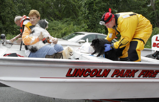 Shirley Larkin, 74, left, of Lincoln Park, N.J., holds one of her dogs, from left, Mickey, Skipper and Gilligan after she was brought to safety by a team of rescue officials, including Alban Ameti, a 