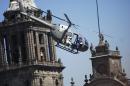 Stunt doubles perform an action scene aboard a helicopter above the Zocalo, Mexico City's main square during the filming of "Spectre," the latest of the James Bond 007 movies, in Mexico, Monday, March 30, 2015. The latest installment of the 007 movie franchise began filming in Mexico City this March. (AP Photo/Sandra Stargardter)