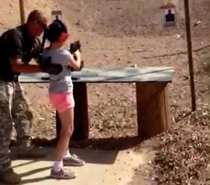 Shooting instructor Charles Vacca stands next to a 9-year-old girl at the Last Stop shooting range in White Hills
