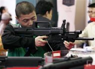 A man holds a gun at an exhibit of weapons at the China International Exhibition on Police Equipment in Beijing in this April 21, 2010 file photo. REUTERS/David Gray/Files