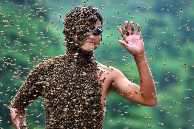 In this photo released by Xinhua News Agency, 20-year-old beekeeper Lu Kongjiang waves as bees cover his body during a contest against 42-year-old Wang Dalin, also a beekeeper, in Longhui County of Sh