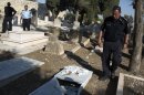 Israeli policemen inspect vandalized tombstones at a Christian cemetery outside Jerusalem's Old City on September 29, 2013