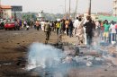 Residents watch smouldering wheel barrow and scorched personal effects in northern Nigeria
