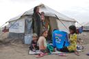 A displaced Syrian family, who fled the city of Hasakeh in eastern Syria due to attacks by the Islamic State group, gathers outside a tent at a refugee camp on July 17, 2015 in the Kurdish town of Derik, on the border with Turkey and Iraq
