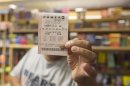 A man holds up his Powerball ticket inside of a convenience store in Chicago, Wednesday, Aug. 7, 2013. Ticketholders are hoping to win Wednesday's Powerball drawing, estimated at $425 million so far. (AP Photo/Scott Eisen)