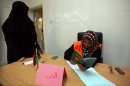 A Libyan woman (L) registers as a voter in the upcoming elections in Tripoli