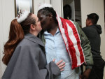Wearing a West Point Cadet's jacket, Jeanette Coleman, left, and her partner Kawane Harris, wearing an Army flight jacket and American flag around her neck, kiss, as Dan Choi, right, looks in his ...