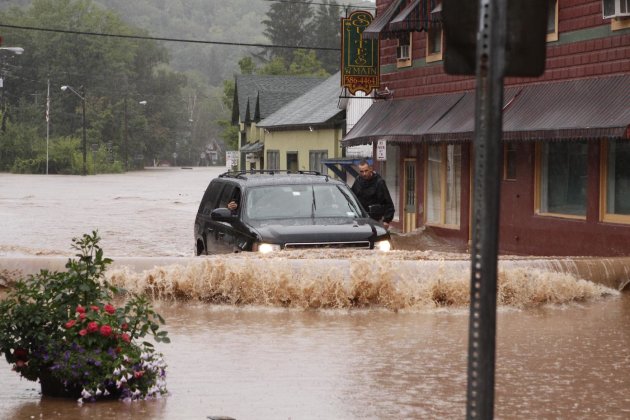 A security guard hangs on the door of Gov. Andrew Cuomo's SUV in the middle of a flooded street Sunday, Aug. 28, 2011, in Margaretville, N.Y. Gov. Cuomo was riding in the SUV, and posted some photos o