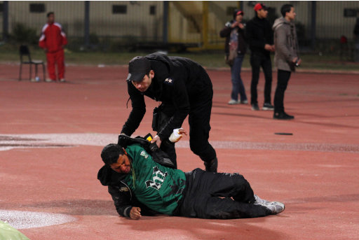 An Egyptian policeman helps an injured football fan during clashes at the football stadium in Port Said, Egypt Wednesday, Feb. 1, 2012. Dozens of Egyptian soccer fans were killed Wednesday in violence following a soccer match in Port Said, when fans flooded the field seconds after a match against a rival team was over, Egypt's Health ministry said. (AP Photo/Ahmed Hassan)