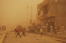 Enveloped by a sand storm, Iraqis clear the debris following two car bombs in the western city of Ramadi