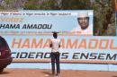 A man standing in front of a campaign poster for presidential candidate Hama Amadou ouside Amadou party's headquarters in Niamey on Febuary 27, 2016