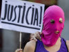 A masked demonstrator stands in front of a placard reading: 'Justice'  in support of the Russian punk group Pussy Riot during a protest outside Spain's Foreign Office in Madrid Thursday Aug. 16, 2012. Three members of Pussy Riot were jailed in March and charged with hooliganism motivated by religious hatred after their punk performance against President Putin in Moscow’s main cathedral. They are awaiting the verdict on Friday, Aug. 17, 2012 (AP Photo/Paul White)