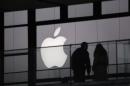 People walk past the Apple logo near an Apple Store at a shopping area in central Beijing