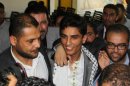 Arab Idol winner Palestinian Mohammed Assaf, center, arrives to the Rafah crossing point on the border between Egypt and southern Gaza Strip, Tuesday, June 25, 2013. Huge crowds of Gazans gave a gleeful welcome Tuesday to the first Palestinian winner of the Arab Idol talent contest, thronging the territory's border crossing with Egypt and the singer's home in hopes of embracing him, but internal politics surfaced quickly. Assaf's victory in the popular contest Saturday sparked huge celebrations in the West Bank and Gaza, giving Palestinians a sense of pride. (AP Photo/Khaled Omar, Pool)