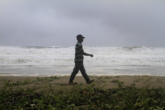 A resident walks along Los Yayales beach as strong waves crash due to the approach of Hurricane Irene to Nagua, in the northern coast of the Dominican Republic, Monday, Aug, 22, 2011. Hurricane Irene churned into a stronger Category 2 storm on Monday evening, after raking Puerto Rico with strong winds and rain that knocked out power to more than a million people, on a track that could carry it to the U.S. Southeast as a major storm by the end of the week. (AP Photo/Roberto Guzman)