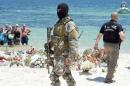A Tunisian special force officer and a policeman patrol the beach as tourists take part in a ceremony on July 3, 2015, in memory of those killed the previous week by a jihadist gunman in the popular resort of Port el Kantaoui
