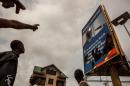 Demonstrators point a broken billboard showing the face of Congolese President Joseph Desiree Kabila during an opposition rally in Kinshasa