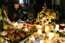 A man lights candles at a makeshift memorial next to the Bataclan concert hall on November 16, 2015 in Paris