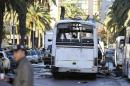 A man walks past the bus that exploded Tuesday in Tunis, Wednesday Nov.25, 2015. Tunisia's president declared a 30-day state of emergency across the country and imposed an overnight curfew for the capital Tuesday after an explosion struck a bus carrying members of the presidential guard, killing at least 12 people and wounding 20 others. (AP Photo)