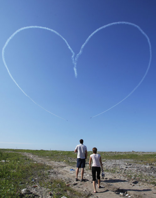 A couple look at a heart painted by smoke from L-39 jets of the "Russ" aerobatic team during an air show at the International Maritime Defence show in St.Petersburg, Russia, Sunday, July 3, 2011. (AP 