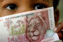A South African child holds a 50 rand note July 2. The rand sank to a fresh low against the dollar i..