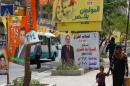 Iraqis walk past electoral campaign posters along a street in Baghdad's Karrada central commercial district on April 7, 2014