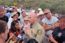 Pinal County Sheriff Paul Babeau speaks to the media as protesters gather near the entrance to juvenile facility in an effort to stop a bus load of Central American immigrant children from being delivered to the facility, Tuesday, July 15, 2014, in Oracle, Ariz. Federal officials delayed the bus with no details on whether the children will arrive or not. (AP Photo/Brian Skoloff)