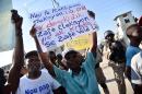 Demonstrators hold up signs during a protest near the parliament in Port-au-Prince, on December 8, 2016
