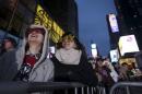 People with 2016 glasses look up as they stand in a penned off area of Times Square during New Year's Eve celebrations in Manhattan