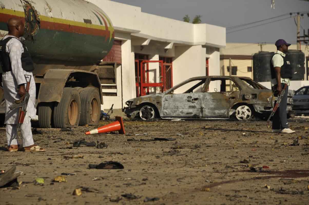 Police officers stand at the site of a blast at a petrol station in Kano, Nigeria. Saturday, Nov. 15, 2014. A bomb exploded Friday night in northern Kano city, the second largest population center in Nigeria, killing six people including three police officers, according to the police. (AP Photo/Muhammed Giginyu)