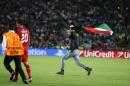 A fan runs onto the pitch holding a palestinian flag during the UEFA Super Cup soccer match between Real Madrid and Sevilla in Cardiff City Stadium, in Cardiff, Wales, Tuesday, Aug. 12, 2014. (AP Photo/Alastair Grant)