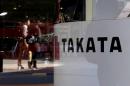 FILE PHOTO - A logo of Takata Corp is seen with its display as people are reflected in a window at a showroom for vehicles in Tokyo