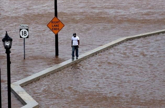 A man walks on top of a wall next  to a flooded highway in New Brunswick, N.J.,  Aug. 28, 2011, as heavy rains left by Hurricane Irene are causing inland flooding of rivers and streams.  Flood waters 