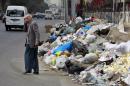 In this Thursday, Dec. 17, 2015 photo, a Lebanese man covers his nose from the smell as he passes by a pile of garbage on a street in Beirut, Lebanon. Lebanon's trash collection crisis which set off summer protests is entering its sixth month, but you would hardly be able to know it in Beirut. (AP Photo/Bilal Hussein)