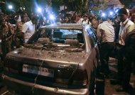 Policemen surround a vehicle which was damaged at the site of an explosion in the Dadar area of Mumbai