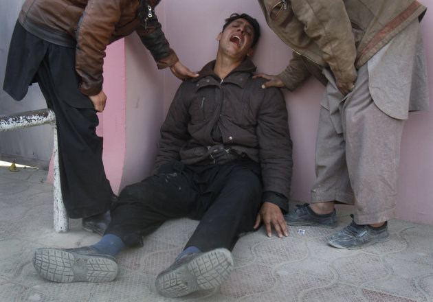 An Afghan man is comforted by relatives outside of a hospital in Kabul, Afghanistan, Tuesday, Dec. 6, 2011. A suicide bomber struck a crowd of Shiite worshippers marking a holy day Tuesday in the Afgh