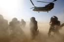 Members of the media try to protect themselves from dust from a British forces transport helicopter as it lands at the forward operating base Sterga II at Helmand province in southern Afghanistan, Monday, Dec. 16, 2013.(AP Photo/Lefteris Pitarakis, pool)