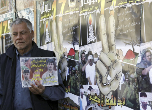 A man holds a picture of a Palestinian jailed in Israel, during a rally marking the annual prisoners' day in the West Bank city of Jenin, Tuesday, April 17, 2012. The Israeli prison service said Tuesday hundreds of Palestinian prisoners have launched a hunger strike to mark the Palestinians' annual prisoners day. Text on picture quotes a poem by Ibrahim Tokan. (AP Photo/Mohammed Ballas)